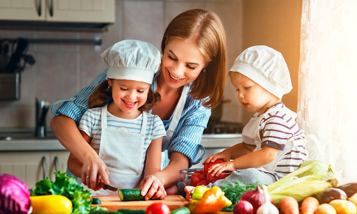 Mãe e seus filhos juntos cozinhando comidas saudáveis, fazendo comida para as crianças.